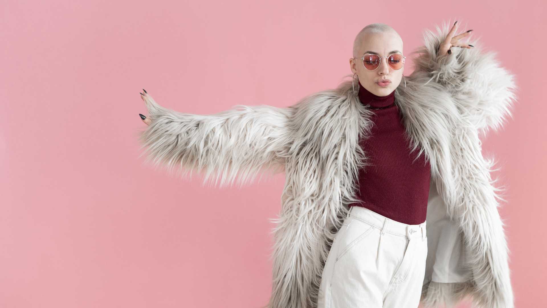 femme avec un manteau blanc devant fond rose